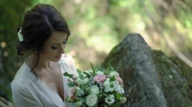 Şelale yakınındaki bir kayaya oturan genç kadın