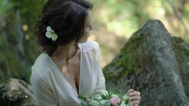 Şelale yakınındaki bir kayaya oturan genç kadın