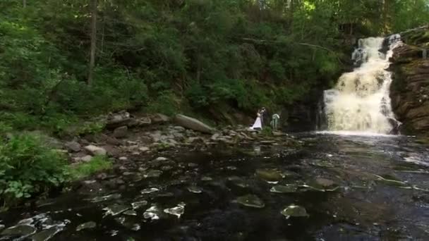 Pareja de boda joven caminando cerca de la cascada — Vídeos de Stock