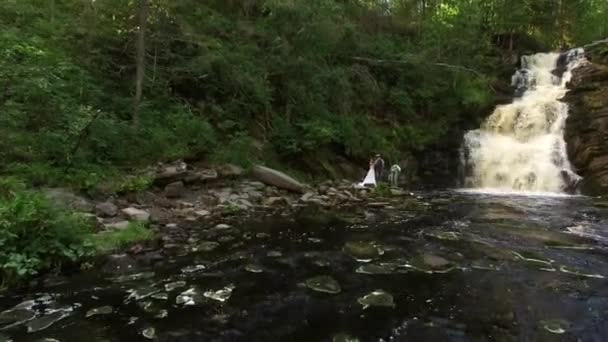 Jeune couple de mariage marchant près de la cascade 
