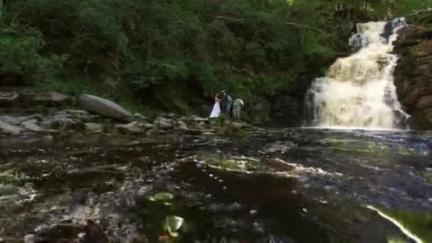 Jeune couple de mariage marchant près de la cascade 