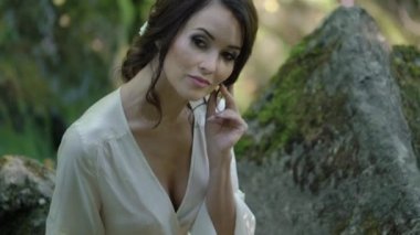 Şelale yakınındaki bir kayaya oturan genç kadın