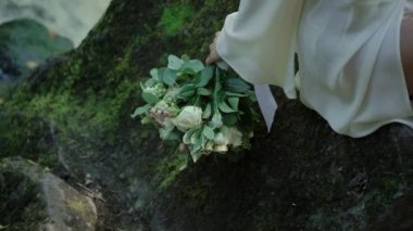 Şelale yakınındaki bir kayaya oturan genç kadın