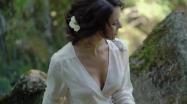 Şelale yakınındaki bir kayaya oturan genç kadın