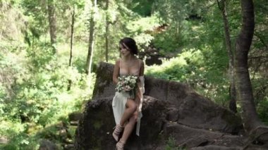 Şelale yakınındaki bir kayaya oturan genç kadın