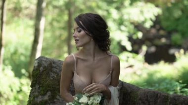 Şelale yakınındaki bir kayaya oturan genç kadın