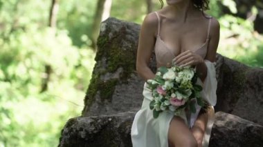 Şelale yakınındaki bir kayaya oturan genç kadın