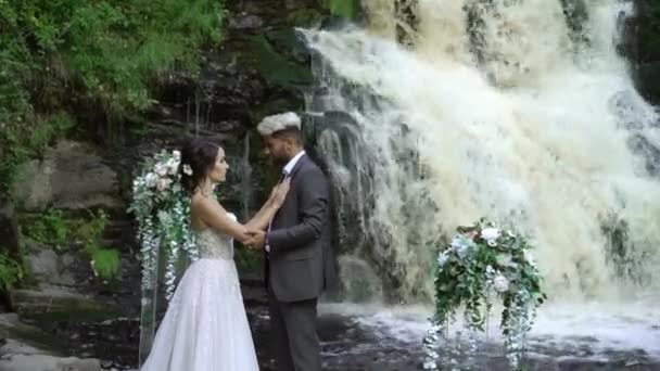 Young wedding couple at ceremony near waterfall — Stock Video