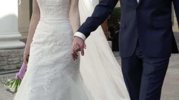 Sposa e sposo che si tengono per mano e camminano in una città — Video Stock