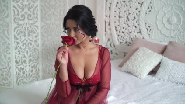 Μελαχρινή νεαρή γυναίκα στα κόκκινα εσώρουχα παίρνει κόκκινο τριαντάφυλλο — Αρχείο Βίντεο