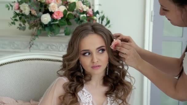 Mulher colocar em flor para o cabelo de jovem bela noiva em lingerie branca — Vídeo de Stock
