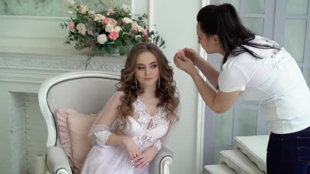 白いランジェリーで若い美しい brideposing の髪に花を置く女性 — ストック動画