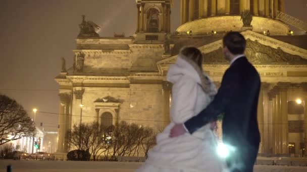 Bruden och brudgummen kramas på vinter natt city — Stockvideo