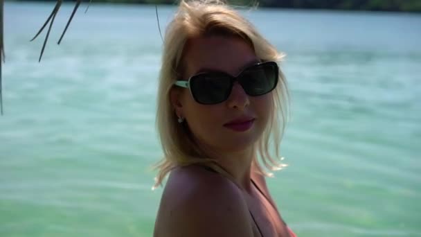 Молода жінка в рожевому купальнику на пляжі — стокове відео