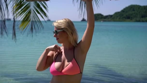 Mujer joven en traje de baño rosa en la playa — Vídeo de stock