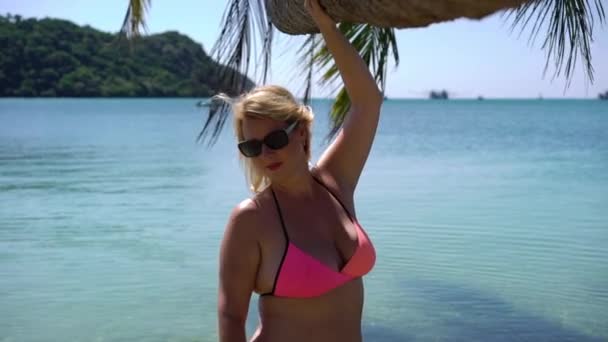 ビーチでピンクの水着の若い女性 — ストック動画
