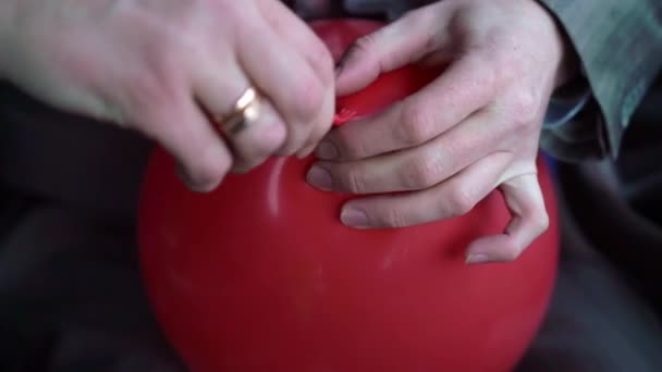 Homem amarrando balão vermelho — Vídeo de Stock