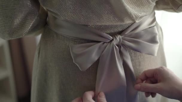 Vrouw zetten beige jurk met strik — Stockvideo