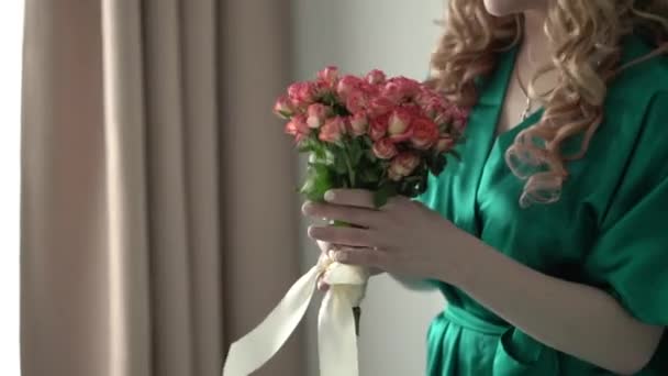 Blonde woman in green bathrobe with bouquet — Stock Video