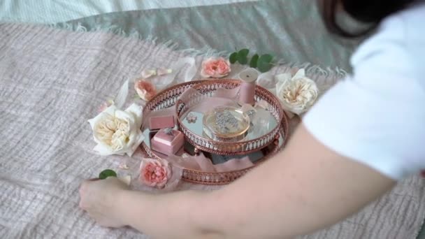 Woman put flowers at pink tray with bridal earrings proposal ring and perfume — Stock Video