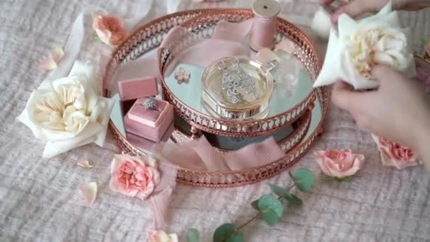 Nő fel virágok rózsaszín tálca, menyasszonyi fülbevaló javaslat gyűrű és a parfüm — Stock videók