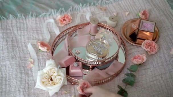 Mujer poner flores en bandeja rosa con pendientes nupciales anillo de propuesta y perfume — Vídeos de Stock