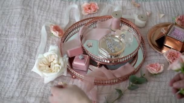 Kvinne satte blomster på rosa brett med gifteøreringer frieri og parfyme – stockvideo