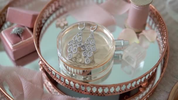 Roze dienblad met bruids oorbellen voorstel ring en parfum — Stockvideo