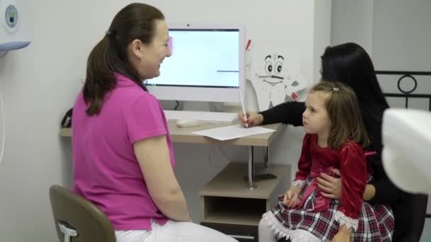 Geduldige moeder met kind ondertekenen van documenten in kliniek — Stockvideo