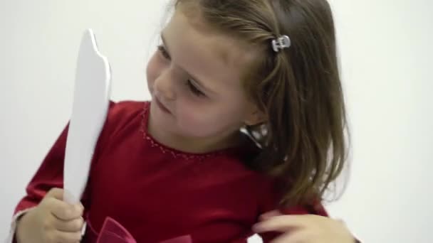 Маленькая девочка в красном платье смотрит в зеркало — стоковое видео
