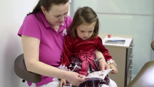 Fata mica si medicul dentist se uita la carti cu autocolante — Videoclip de stoc