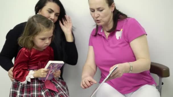 Malá holka a zubař doktor pozoroval knihy se samolepkami — Stock video