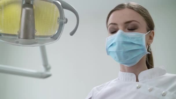 Tandarts doctor in de tandheelkundige kliniek licht lamp en werken met hulpprogramma's inschakelen — Stockvideo