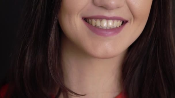 Junge brünette Frau lächelt und spricht auf schwarzem Hintergrund — Stockvideo