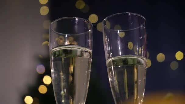 Twee glazen champagne. Mousserende wijn op de achtergrond van Kerstmis of Nieuwjaar slinger. Vakantieverlichting — Stockvideo