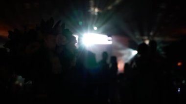 Partideki insanlar dans ediyor. Disko ışıklarıyla gece kulübünde tanınmayan siluet kalabalığı
