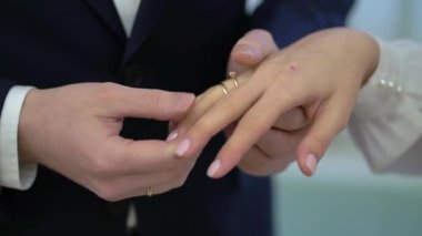 Gelin ve damat törende alyanslarını değiş tokuş ederler. Hoş bir çift.