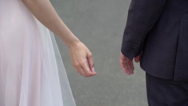Svatební pár ve městě. Nevěsta a ženich se drží za ruce — Stock video