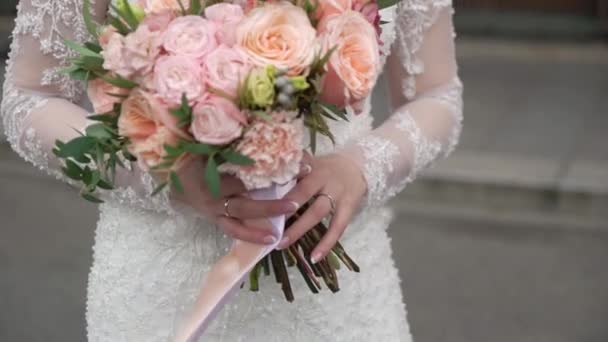 Jonge bruid in trouwjurk met boeket bloemen in een stad. Witte luxe jurk mode — Stockvideo