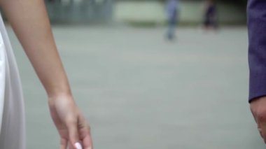 Şehirde bir düğün çifti. Gelin ve damat el ele tutuşuyorlar.