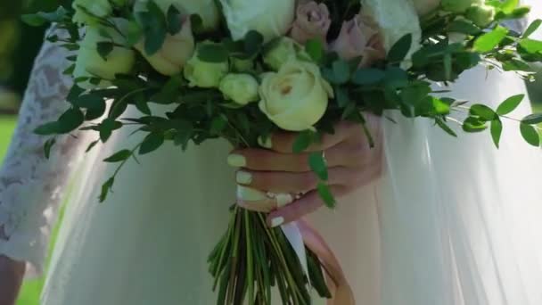 Giovane sposa in abito da sposa che tiene fiori bouquet in un parco. Bianco moda abito di lusso — Video Stock