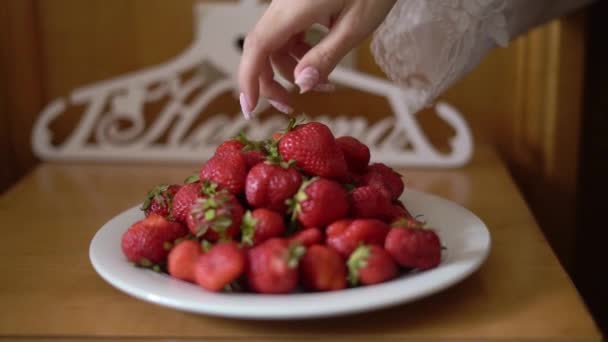 ผู้หญิงสาวเอาสตรอเบอร์รี่หวานสีแดงจากจานและกิน — วีดีโอสต็อก