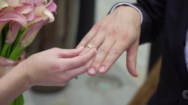 Gelin ve damat törende alyanslarını değiş tokuş ederler. Hoş bir çift.