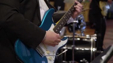 Gitarist konserde gitar çalıyor. Sahnede telli enstrümanlı müzisyen.