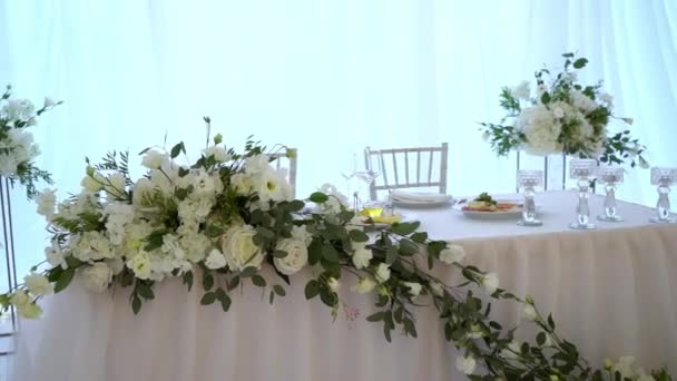 चष्मा, प्लेट्स, कटलरी आणि नॅपकिन्स. पार्टीसाठी फुलांसह सजवलेल्या टेबल. लग्न रिसेप्शन, वाढदिवस, वर्धापनदिन . — स्टॉक व्हिडिओ