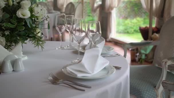 Bicchieri, piatti, posate e tovaglioli. Tavoli decorati con fiori per la festa. Ricevimento di nozze, compleanno, anniversario. — Video Stock