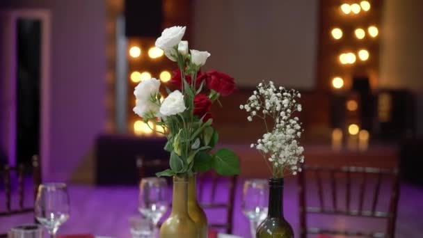 Glasögon, tallrikar, Bestick och servetter. Dekorerade bord med blommor för festen. Bröllopsmottagning, födelsedag, årsdag. — Stockvideo