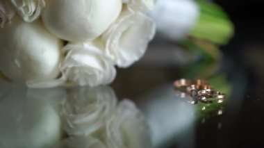 Evlilik yüzükleri. Bir çift evlilik sembolü. Gelin ve damadın karı koca olma aşkı. Evlilik sembolü. Gelin buketi çiçekleri