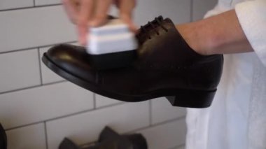 Adam ayakkabılarını kremle temizleyip parlatıyor. Sabahleyin bornozlu bir erkek..