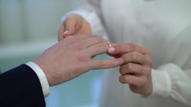 Gelin ve damat törende alyanslarını değiş tokuş ederler. Hoş bir çift.